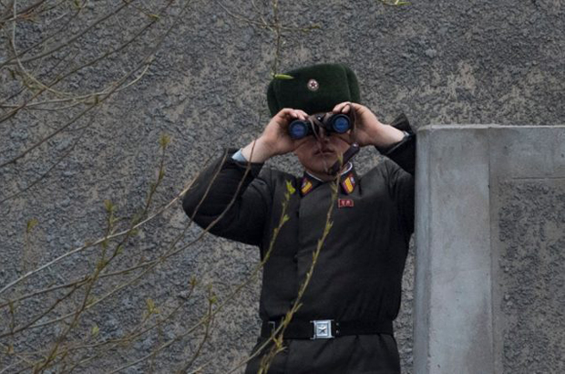 Um soldado norte-coreano usa binóculos para observar a outra margem do rio Yalu, perto de Sinuiju, na fronteira com a cidade chinesa de Dandong, em 14 de abril de 2017. (Johannes Eisele/AFP/Getty Images)