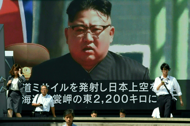 Pedestres caminham em frente a um telão em Tóquio que transmite notícias sobre o líder norte-coreano Kim Jong-un, após um teste de míssil norte-coreano que passou sobre o Japão em 15 de setembro de 2017 (Toru Yamanaka/AFP/Getty Images)