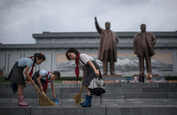 Estudantes limpam degraus em frente às estátuas de Kim Il-Sung e Kim Jong-Il, antigos ditadores da Coreia do Norte, em Pyongyang, em 27 de julho de 2017. A Coreia do Norte está censurando as mensagens que podem ser transmitidas no Dia das Mães, dia em que se homenageiam as mães que educam seus filhos para serem "bons revolucionários socialistas" (Ed Jones/AFP/Getty Images)