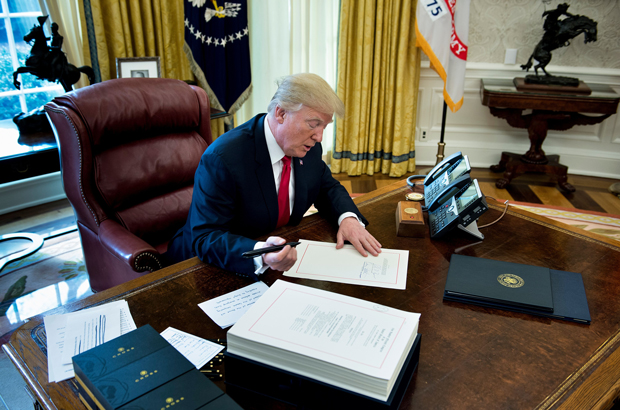 O presidente estadunidense Donald Trump assina a Lei de Reforma e Corte de Impostos no Salão Oval da Casa Branca em Washington, D.C., em 22 de dezembro de 2017 (Brendan Smialowski/AFP/Getty Images)