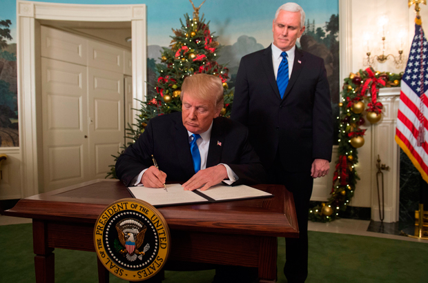 O presidente estadunidense Donald Trump assina uma proclamação depois de fazer uma declaração sobre Jerusalém na Sala de Recepção Diplomática da Casa Branca em 6 de dezembro de 2017 (Saul Loeb/AFP/Getty Images)