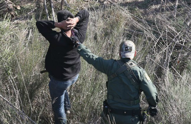 Agente de fronteira norte-americano surpreende homem que estava escondido entre arbustos e pretendia atravessar ilegalmente a fronteira mexicana em La Grulla, no Texas, em 10 de dezembro de 2015 (John Moore/Getty Images)