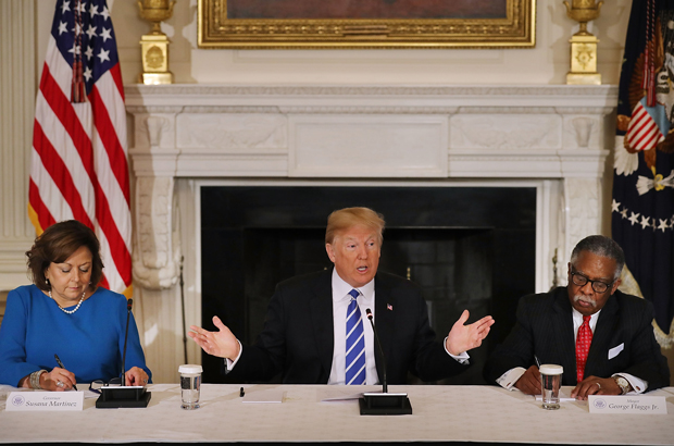 O presidente norte-americano Donald Trump (centro) é acompanhado da governadora do Novo México, Susana Martinez (esq.), e o prefeito de Vicksburg, no Mississippi, George Flaggs Jr., durante uma mesa redonda com autoridades estaduais e locais para revelar o longamente esperado plano de infraestrutura da gestão Trump, no Salão de Jantar da Casa Branca em Washington, D.C., em 12 de fevereiro de 2018 (Chip Somodevilla/Getty Images)