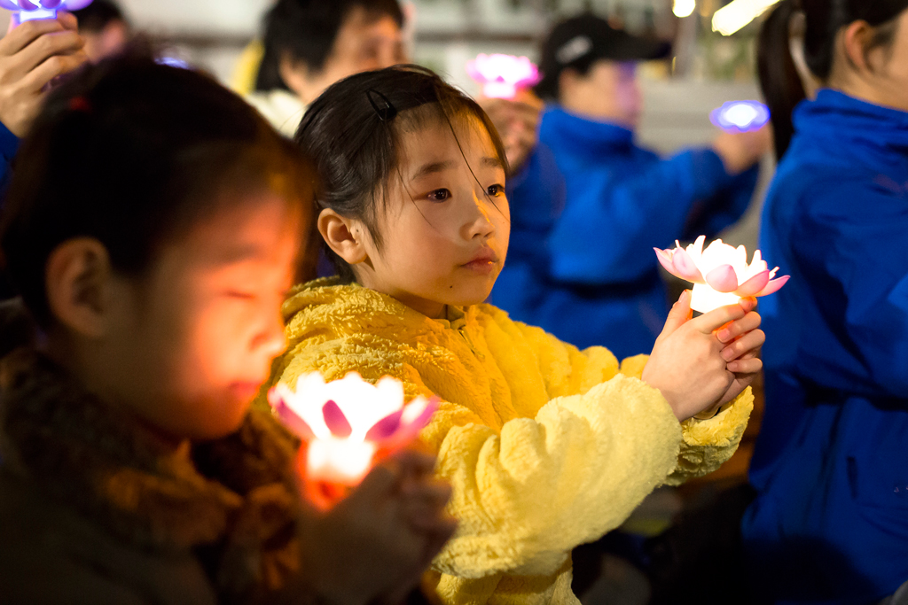 Jovens praticantes da disciplina espiritual do Falun Gong realizam uma vigília de velas perto do consulado chinês em Nova York em protesto contra a brutal repressão e perseguição do regime chinês contra os adeptos na China; em 23 de abril de 2017 (Samira Bouaou/The Epoch Times)