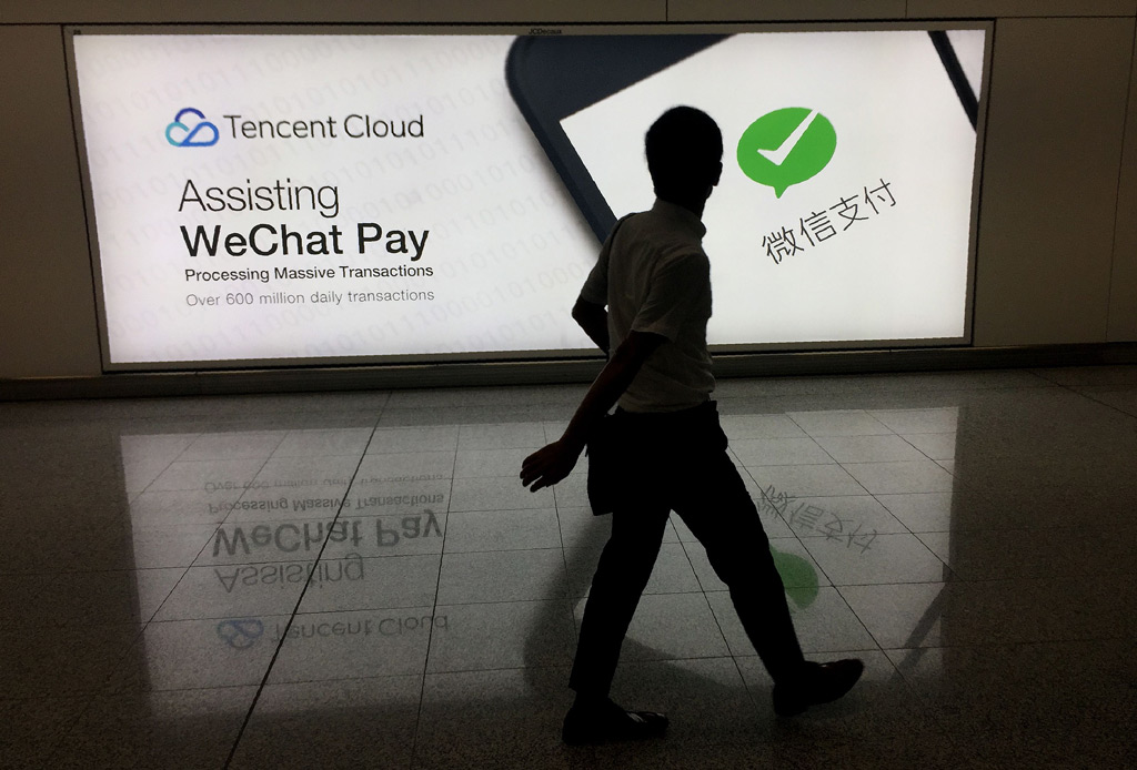 Um homem chinês caminha no aeroporto internacional de Hong Kong enquanto passa por um anúncio da plataforma de mídia social WeChat, de propriedade da Tencent, em 21 de agosto de 2017 (Richard A. Brooks/AFP/Getty Images)