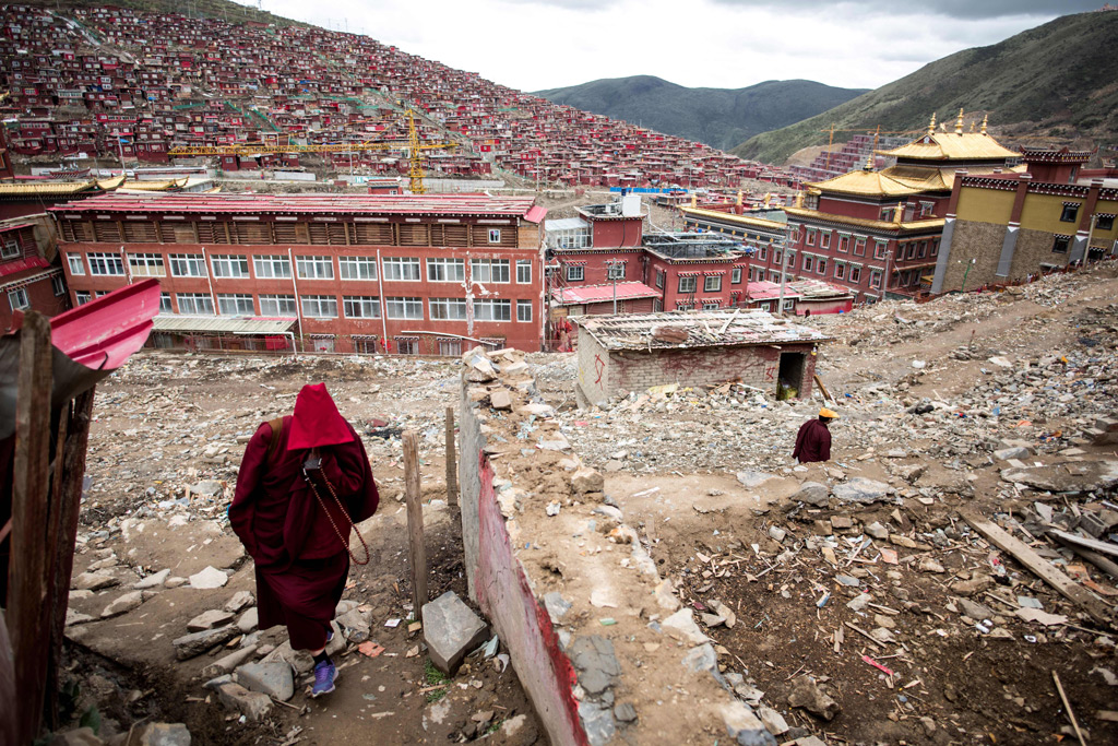 Uma monja caminha entre detritos de casas demolidas na mais importante instituição mundial de ensino do budismo tibetano, o monastério Larung Gar, no condado de Sertar, na província de Sichuan, no Sudoeste da China, em 29 de maio de 2017. O regime chinês ordenou e tem conduzido essas demolições desde 2016 (Johannes Eisele/AFP/Getty Images)
