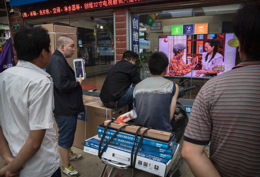 Homens assistem a um programa numa televisão na vitrine de uma loja de eletrônicos na cidade de Wuhan, província de Hubei, em 15 de maio de 2017 (Kevin Frayer/Getty Images)