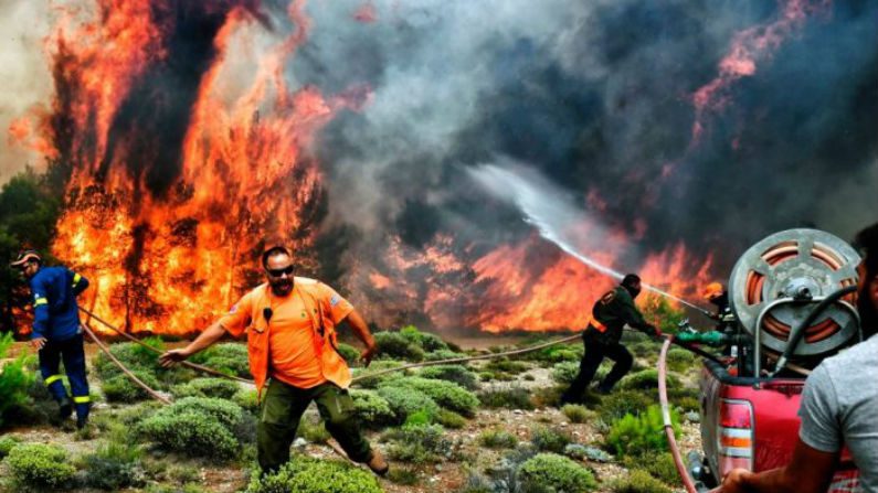 Bombeiros e voluntários tentam extinguir chamas durante um incêndio na vila de Kineta, perto de Atenas, em 24 de julho de 2018 (Valerie Gache / AFP / Getty Images)