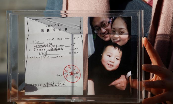 Li Wenzu, esposa do proeminente advogado de direitos humanos chinês Wang Quanzhang, segura uma caixa com uma foto de família e o aviso de detenção do marido antes de raspar a cabeça em protesto em Pequim, China, 17 de dezembro de 2018 (Thomas Peter / Reuters)