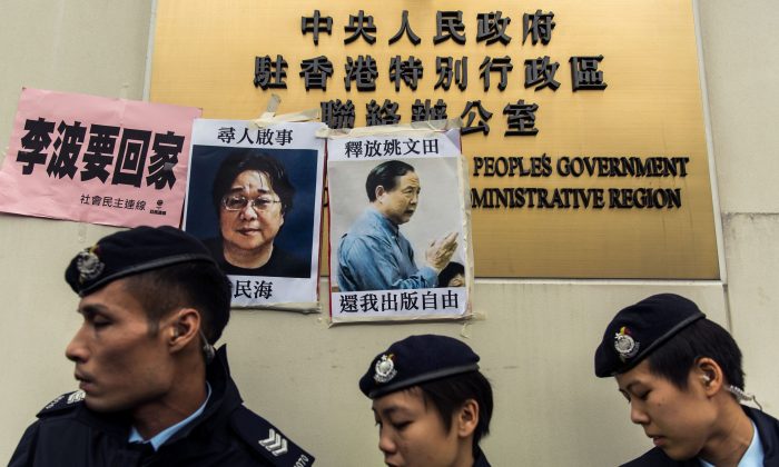 Polícia frente a cartazes dos desaparecidos Gui Minhai (esq.), um dos cinco proprietários da editora Mighty Current, e Yau Wentian (dir.), editor proveniente de Hong Kong que foi preso no ano passado enquanto se preparava para publicar um livro criticando a liderança chinesa. Os anúncios foram afixados em um pôster no Escritório de Ligação da China em Hong Kong em 3 de janeiro de 2016 (Anthony Wallace/AFP/Getty Images)