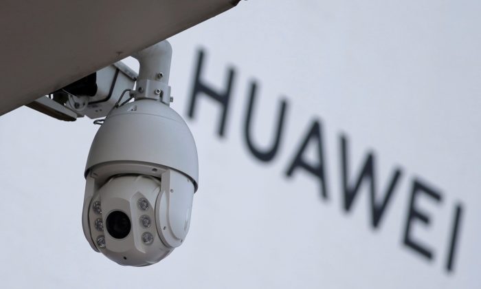 Uma câmera de vigilância é vista ao lado de uma placa da Huawei fora de um shopping center em Pequim, em 29 de janeiro de 2019 (Jason Lee / Reuters)