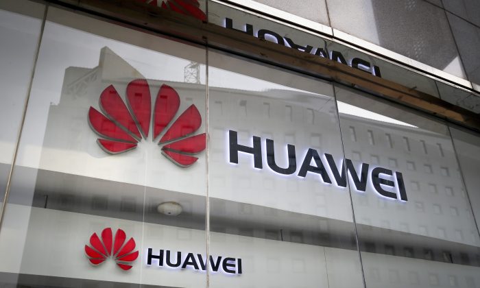 Os logotipos da Huawei são exibidos na vitrine da loja de varejo, refletindo o escritório do Ministério das Relações Exteriores em Pequim, em 29 de janeiro de 2019 (Andy Wong / AP)