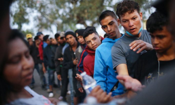 Migrantes esperam para receber alimentos e água doados fora de um abrigo temporário montado para membros da caravana de migrantes em Tijuana, no México, em 28 de novembro de 2018 (Mario Tama / Getty Images)