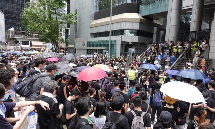 Manifestantes cercam a sede da polícia de Hong Kong, em 21 de junho de 2019, em protesto contra a controversa legislação de extradição que facilitaria a erosão das liberdades das cidades pela China continental (Yu Gang / The Epoch Times)