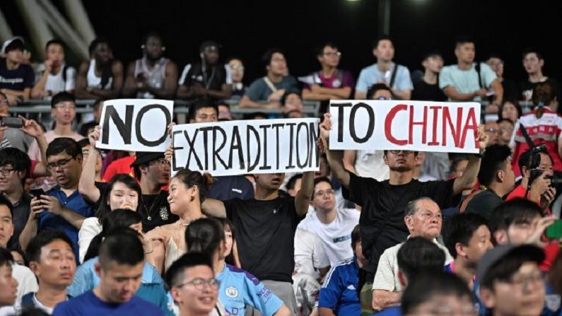 Manifestantes detêm cartazes relacionados aos recentes acontecimentos políticos no território, durante partida de futebol entre o Manchester City, clube da Premier League inglesa, e Kitchee, do Hong Kong, no Estádio Hong Kong, em 24 de julho de 2019 (Anthony Wallace / AFP / Getty Images)
