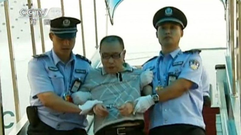 Uma captura de tela feita em 23 de julho de 2011 da Televisão Central da China mostra o empresário chinês fugitivo Lai Changx ing sendo escoltado pela polícia após aterrissar em Pequim a bordo de um voo civil sob a custódia da polícia canadense (CCTV / STR / AFP / Getty Images)