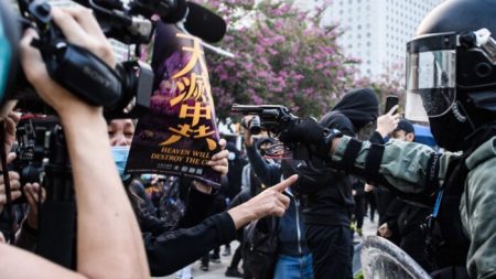 Policial aponta arma para manifestante que segurava cartaz do Epoch Times em Hong Kong 