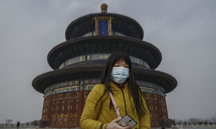 Uma visitante chinesa usa uma máscara protetora enquanto percorre os terrenos do Templo do Céu em Pequim, China, em 27 de janeiro de 2020 (Kevin Frayer / Getty Images)