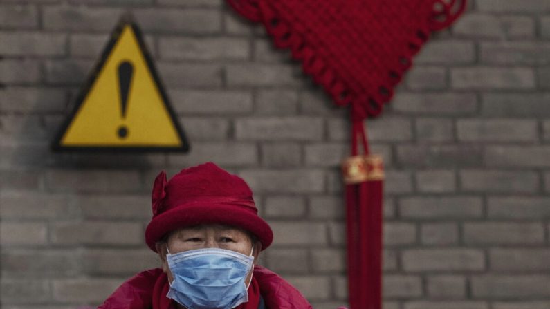 Um visitante chinês usa uma máscara protetora enquanto percorre os terrenos do Templo do Céu, que permaneceu aberto durante o feriado do Ano Novo Chinês em Pequim, China, em 27 de janeiro de 2020 (Kevin Frayer / Getty Images)