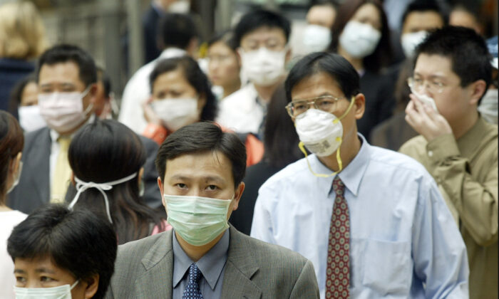 Pessoas usam máscaras na rua para se proteger contra um vírus mortal de pneumonia em Hong Kong, em 31 de março de 2003 (Peter Parks / AFP / GettyImages)