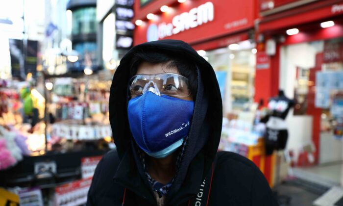 Um homem de máscara para ajudar impedir a propagação do coronavírus (COVID-19) caminha ao longo do distrito comercial de Myungdong em Seul, Coreia do Sul, em 23 de fevereiro de 2020 (Chung Sung-Jun / Getty Images)