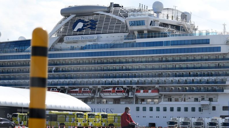 Um homem passa por ônibus urbanos alinhados para transportar o primeiro lote de passageiros que desembarca do navio Diamond Princess no terminal de cruzeiros Daikoku Pier em Yokohama, em 19 de fevereiro de 2020 (Charly Triballeau / AFP via Getty Images)