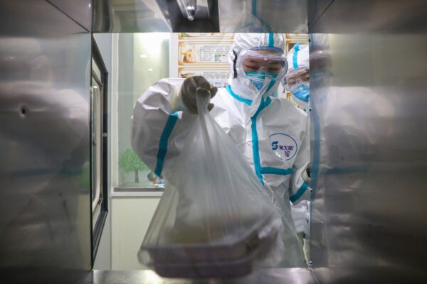 Equipe médica recebendo lancheiras para pacientes através de uma janela em uma sala de isolamento de um hospital de Wuhan, na província central de Hubei, China, durante o surto do vírus na cidade, em 30 de janeiro de 2020 ( STR / AFP via Getty Images)