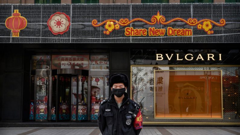 Um segurança chinês usa uma máscara protetora em pé em uma rua comercial de Pequim, China, em 18 de fevereiro de 2020 (Kevin Frayer / Getty Images)