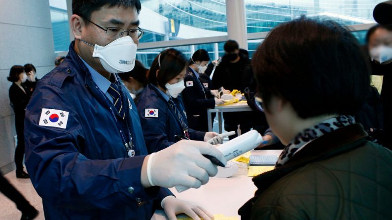 Nesta imagem fornecida pelos Centros da Coreia do Sul para Controle e Prevenção de Doenças, o oficial verifica os passageiros em um voo de Wuhan que deixou o Aeroporto Internacional de Incheon em 22 de janeiro de 2020 em Incheon, na Coreia do Sul (Foto dos Centros Coreanos de Controle e Prevenção de Doenças via Getty Images)