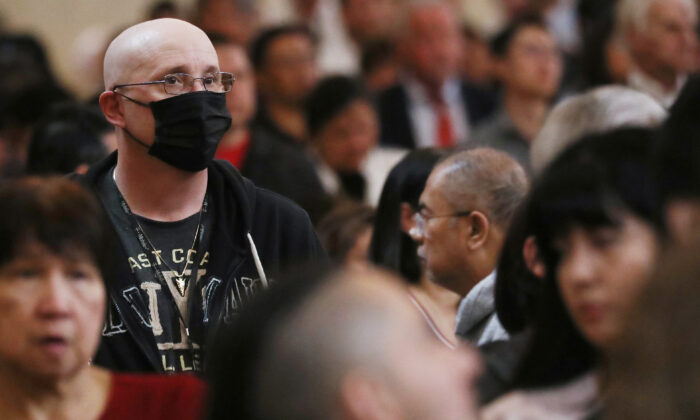 Um homem (esquerda) usa uma máscara para proteger contra o coronavírus enquanto senta em um banco na Catedral de Nossa Senhora dos Anjos, na quarta-feira de cinzas, em 26 de fevereiro de 2020 em Los Angeles, Califórnia (Mario Tama / Getty Images)