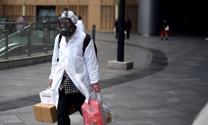 Um homem de máscara carrega itens que comprou em um supermercado em Wuhan, China, em 30 de março de 2020 (NOEL CELIS / AFP via Getty Images)