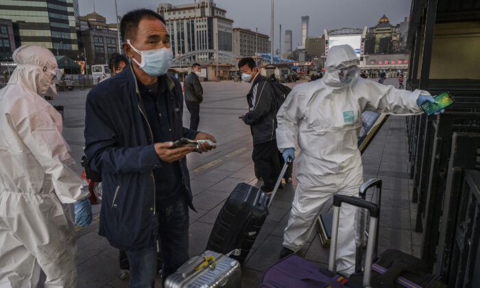 Pessoas usam máscaras e roupas protetoras ao chegarem à Estação Ferroviária de Pequim, em Pequim, China, em 13 de março de 2020 (Kevin Frayer / Getty Images)