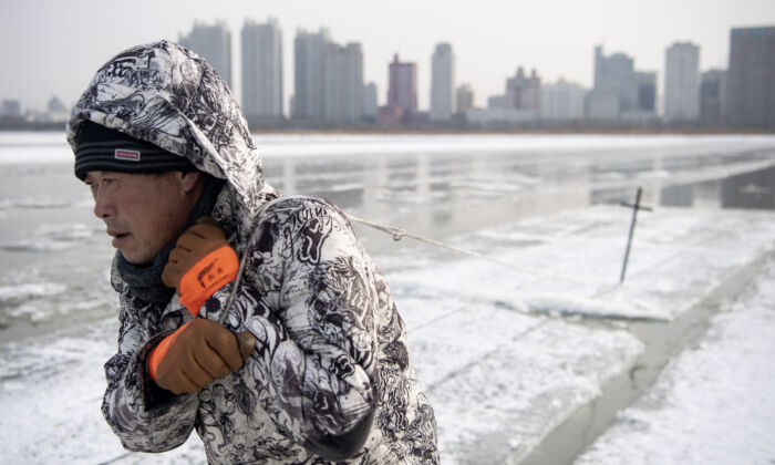 Um trabalhador arrasta blocos de gelo no rio Songhua congelado em Harbin, na China, em 11 de dezembro de 2019 (NOEL CELIS / AFP via Getty Images)