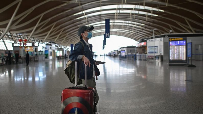 Um passageiro olha para uma tela no Aeroporto Internacional Pudong de Xangai, em Xangai, China, em 19 de março de 2020 (HECTOR RETAMAL / AFP via Getty Images)