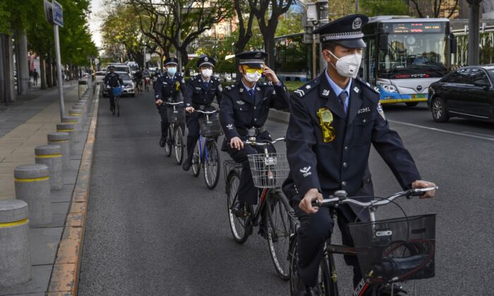 Oficiais chineses andam juntos de bicicleta em uma área comercial em Pequim, China, em 22 de abril de 2020 (Kevin Frayer / Getty Images)