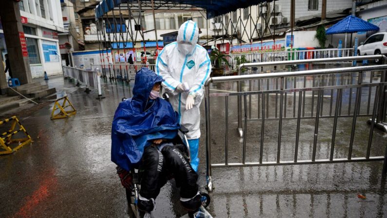 Um trabalhador médico ajuda um homem que procura tratamento em uma clínica de febre no Hospital Huanggang Zhongxin em Huanggang, província de Hubei, no centro da China, em 27 de março de 2020 (Noel Celis / AFP via Getty Images)