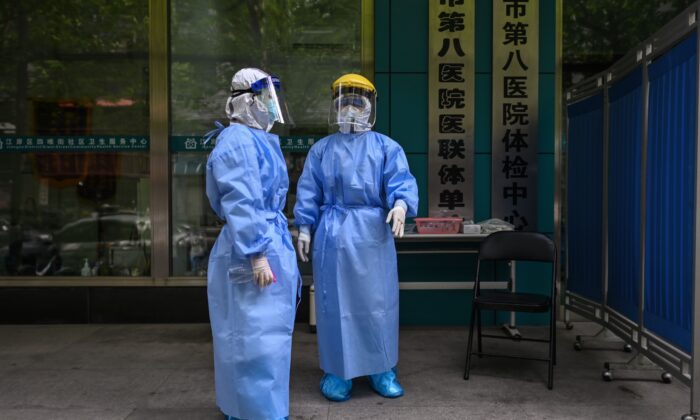 Trabalhadores médicos são vistos colhendo amostras de swab de pessoas para serem testadas para o novo coronavírus COVID-19 em Wuhan, província central de Hubei, na China, em 16 de abril de 2020 (Hector Retamal / AFP via Getty Images)