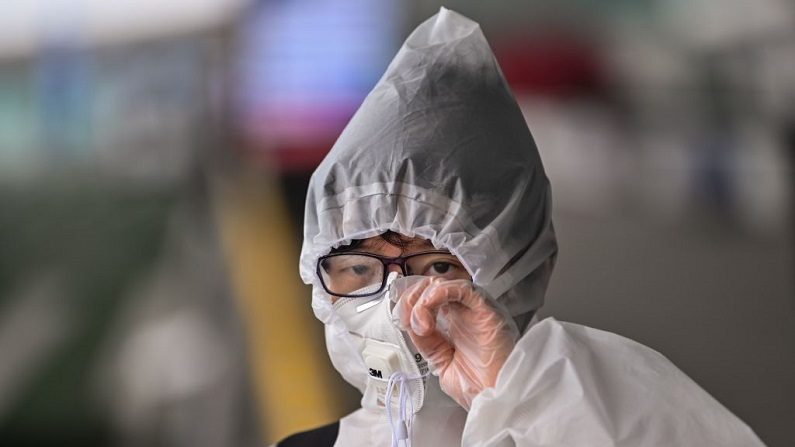 Um passageiro em traje de proteção e máscara facial perto de uma entrada para o Aeroporto de Tianhe em Wuhan, província central de Hubei, na China, em 11 de abril de 2020 (Hector RETAMAL / AFP via Getty Images)