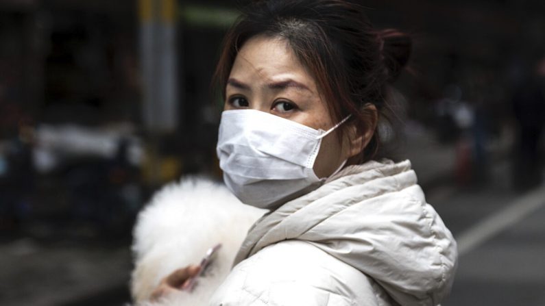 Uma mulher segurando um cachorro na rua em Wuhan, província de Hubei, China, em 11 de abril de 2020 (Getty Images)