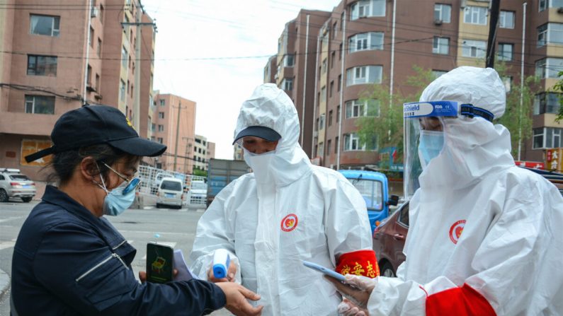 Funcionários avaliam a temperatura corporal de um residente fora de um complexo residencial na cidade de Jilin, China, em 25 de maio de 2020 (STR / AFP via Getty Images)