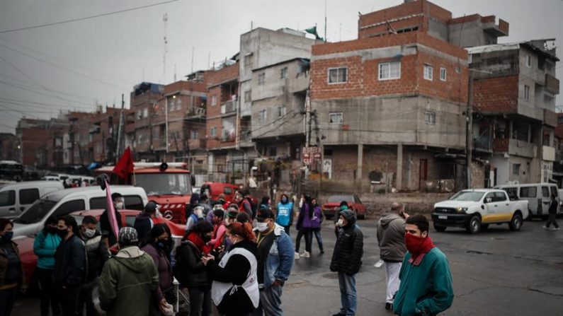 Um grupo de pessoas espera por comida na frente de uma sala de jantar da comunidade durante a crise dos coronavírus nesta sexta-feira no bairro Padre Rodolfo Ricciardelli, anteriormente conhecido como Villa 1-11-14, na cidade de Buenos Aires (EFE / Juan Ignacio Roncoroni)