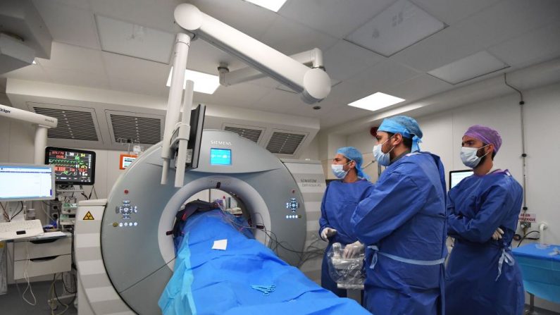 O radiologista Gilles Piana (centro) e seus assistentes ao lado de um paciente antes de um exame em 7 de novembro de 2017, em Marselha, sul da França, na unidade de oncologia e radiologia do Instituto Paoli-Calmette, um centro de tratamento de câncer (ANNE-CHRISTINE POUJOULAT / AFP via Getty Images)