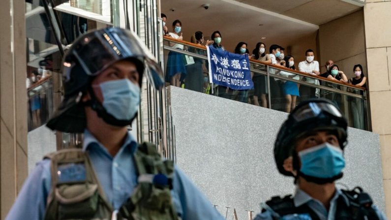 Os apoiadores da democracia seguram uma bandeira da Independência de Hong Kong e gritam slogans durante uma manifestação contra a lei de segurança nacional, enquanto a polícia de choque protege uma área em um shopping center em 30 de junho de 2020 em Hong Kong. Pequim aprovou a controversa lei de segurança nacional que ameaçará a autonomia e as liberdades políticas da cidade (Anthony Kwan / Getty Images)