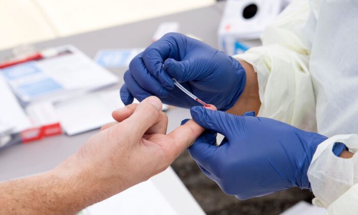 Um profissional de saúde tira uma gota de sangue para um teste de anticorpo contra a COVID-19 (Valerie Macon / AFP via Getty Images)