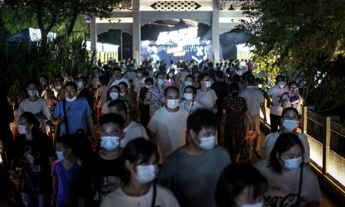 Residentes de Wuhan, província de Hubei, China, usam máscaras faciais ao passarem pela entrada do Festival da Cerveja em 21 de agosto de 2020 (Getty Images)