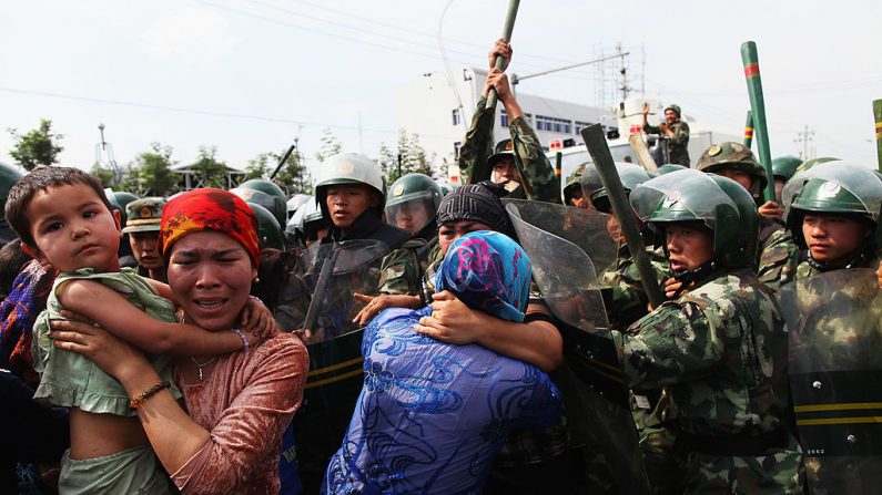 Policiais chineses empurram mulheres uigures que protestavam em uma rua em 7 de julho de 2009 em Urumqi, capital da região autônoma uigur de Xinjiang na China (Imagens Guang Niu / Getty)