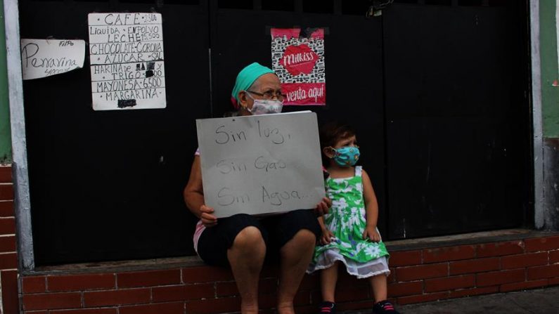 Mulher segura placa de protesto apelando à falta de água, gás e eletricidade, dia 23 de setembro de 2020, em San Cristóbal (EFE / Johnny Parra)