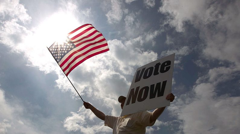 JayDanny Cooper insta os residentes do Alabama a votarem nas primárias ao longo da beira de uma rodovia em 13 de março de 2012 em Birmingham, Alabama. À medida que a corrida por delegados continua, os eleitores no Alabama e Mississippi votarão nas primárias de hoje (Foto de Win McNamee / Getty Images)
