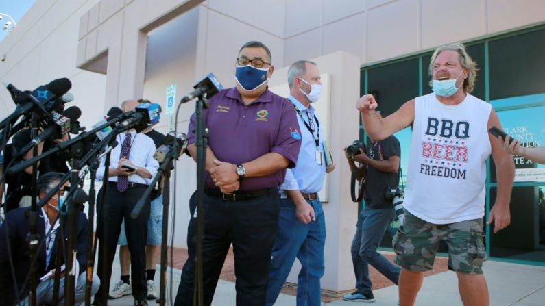 O secretário de eleitores do Condado de Clark, Joe Gloria, à esquerda, é interrompido por um membro do público descontente durante uma entrevista coletiva fora do Departamento Eleitoral do Condado de Clark (Foto: RONDA CHURCHILL / AFP via Getty Images)