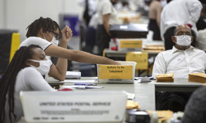 Uma funcionária do Departamento de Eleições de Detroit classifica os votos ausentes no Conselho de Contagem Central do TCF Center em Detroit, Michigan, em 4 de novembro de 2020 (Elaine Cromie / Getty Images)